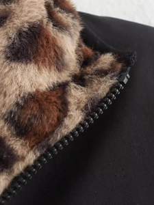 Detail of a black zipper on a reversible bomber jacket with leopard faux fur lining