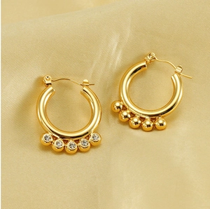 Detail of 18K gold geometric earrings featuring pearls and rhinestones on satin
