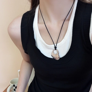 Detail view of a silver liquid metal heart pendant on a minimalist black cord necklace