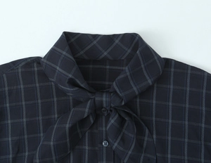 Detailed close-up of navy plaid poplin shirt featuring a tied bow neckline and buttons