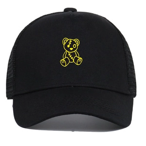 Detail view of a black trucker hat featuring a yellow stitched bear patch and mesh back