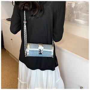 Detailed close-up of blue tweed cylinder bag with silver metal chain and lock buckle
