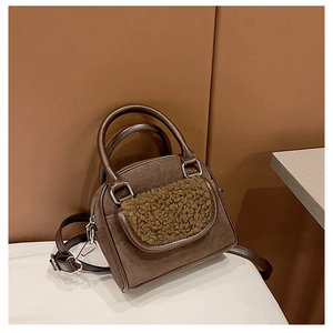 Detail of brown teddy fur patch and smooth faux leather texture on minimalist handbag