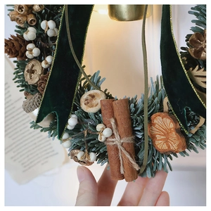 Detail of Christmas wreath with green pine needles, cinnamon sticks and velvet ribbon