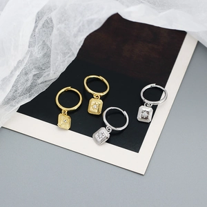 Detailed view of silver and gold eight-pointed star earrings on elegant fabric