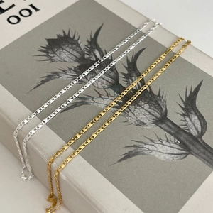 Detail of gold and silver pig nose anchor chains on a book, showing polished link texture