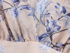 Détail du tissu en mousseline beige avec imprimé fleuri bleu sur robe à col en V