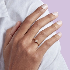 Close-up of a delicate 18K gold ring with zircon stones worn on a female hand