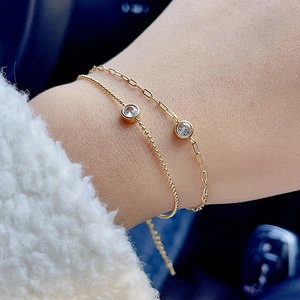 Close-up of double layered 18k gold plated paperclip and ball chain bracelets with zircon