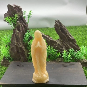 Macro detail of a 10cm hand-carved yellow gemstone Virgin Mary statue in prayer