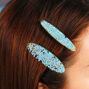 Detalle de pinzas para el cabello de resina con purpurina de estrellas y corazones láser