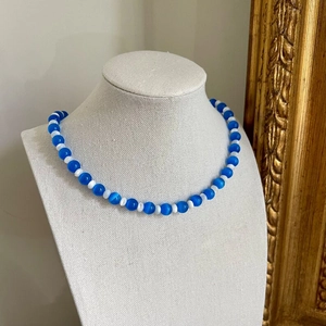 Detail of blue and white cat-eye beaded necklace with elegant heart pendant on neck model