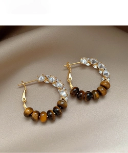 Macro detail of bohemian tiger eye bead earrings with sparkling zircon inlay