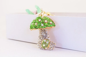Detail of colorful mushroom keychain with green and clear rhinestones on gold metal