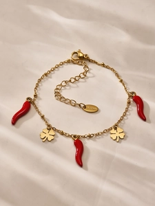 Detailed view of gold stainless steel bracelet with red chili and clover charms