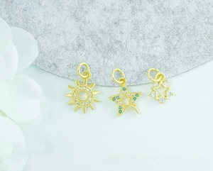 Detailed view of 18K gold plated sun, moon, and star pendants with inlaid zircon stones