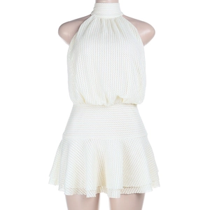 Detail of white knit halter neck dress showing textured openwork and tiered ruffle hem