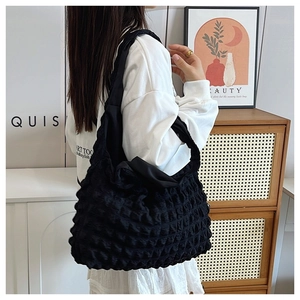 Detail of black cloud pleated shoulder bag with waffle texture shown on model