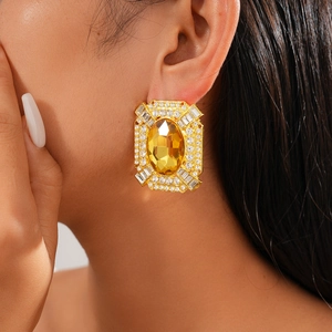 Détail d'une boucle d'oreille en cristal jaune ovale avec strass pavés style baroque