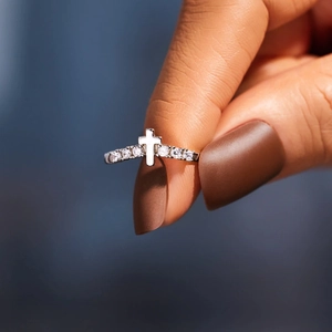 Macro shot of silver cross ring with sparkling zircon stones held on a finger