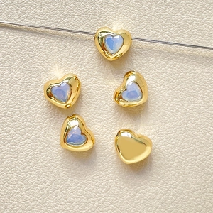 Vista macro di perline a cuore placcate oro 18k con zircone blu per gioielli fai da te