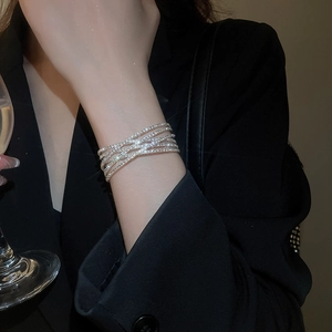 Close-up of sparkling multilayer diamond-set bracelet with pearls on a model's wrist