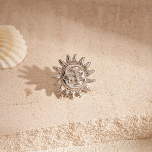 Macro shot of silver celestial sun and moon face earring on natural stone background