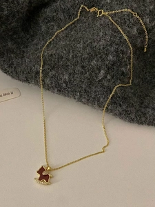 Detail view of 18K gold plated horse necklace with red enamel and sparkling zircons