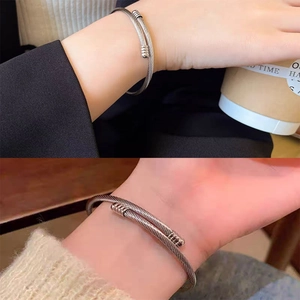 Minimalist silver stainless steel cable bracelet with textured cylindrical ends on wrist