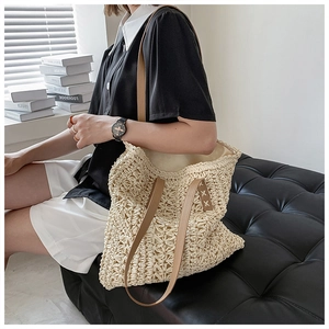 Close-up of beige crochet tote bag with woven hollow patterns and brown leather straps