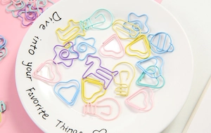 Close-up of assorted star and heart shaped metal paperclips on a ceramic tray