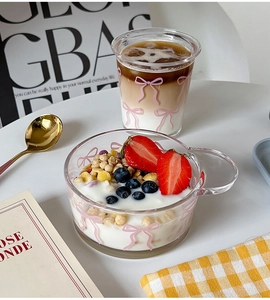 Close-up of glass bowl and cup set with pink bow patterns holding yogurt and coffee