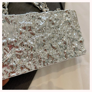 Close-up of silver acrylic box bag featuring liquid metal texture and chunky chain strap