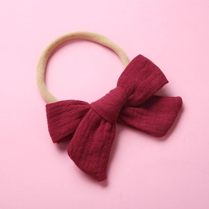 Close-up of baby nylon headband with a large textured dark red muslin cotton bow