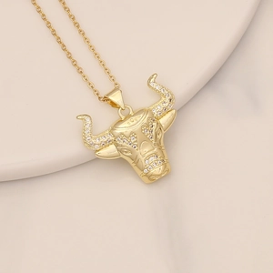 Close-up of golden bull head pendant with micro-pave cubic zirconia on beige tray
