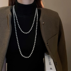 Elegant multi-layered long faux pearl necklace shown on a model in a sophisticated style