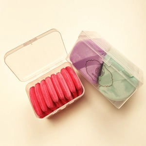 Macro view of colorful velvet makeup puffs in transparent plastic storage boxes