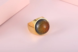 Macro shot of gold stainless steel ring featuring a large nebula effect glass gemstone