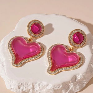 Macro detail of pink resin heart earrings with sparkling rhinestone borders and gold finish