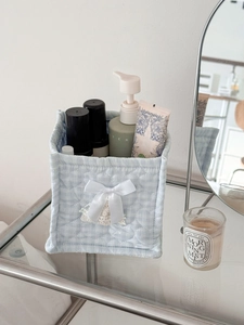 Close-up of a light blue quilted square storage basket with white bow and lace detail