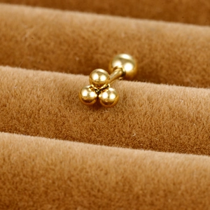 Macro shot of three golden stainless steel ball clusters on a brown velvet stand