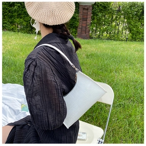 Outdoor shot showing a white crocodile pattern shoulder bag worn by a model