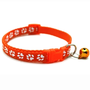 Detail of orange pet collar with paw prints featuring a buckle and gold bell