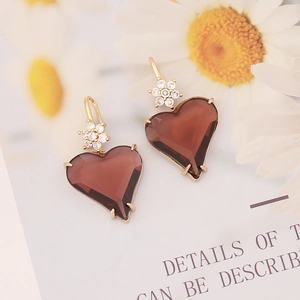 Close-up of wine red heart pendant earrings with gold floral studs and cubic zirconia