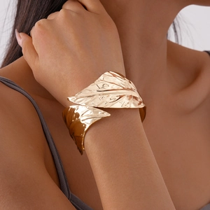 Macro detail of golden leaf-shaped cuff bracelet with intricate vein texture on model