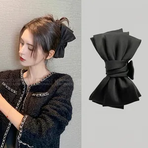 Detail of a large black velvet bow hair claw clip showing smooth satin texture and size