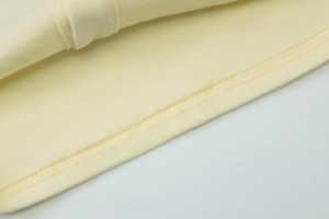 Detailed close-up showing the professional overlock stitching on the yellow knit fabric