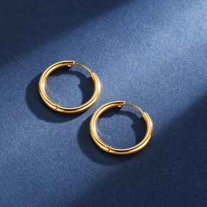 Detailed view of polished golden stainless steel hoop earrings on blue textured card