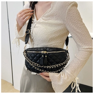 Close-up of black quilted chest bag featuring gold chain details and adjustable strap