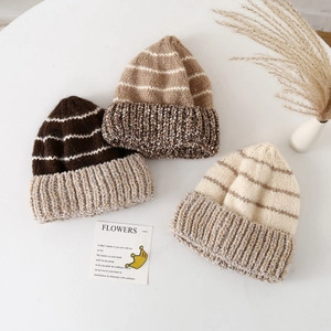 Dettaglio di berretti in maglia a righe spesse nei colori marrone, kaki e beige per l'inverno